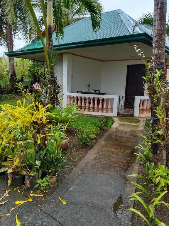 a white house with a porch and some plants at Jupiters Garden Cottages in Lawa-an