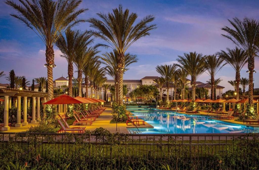 a resort pool with chairs and palm trees at night at Irvine Spectrum 1 bed 1 bath in Irvine