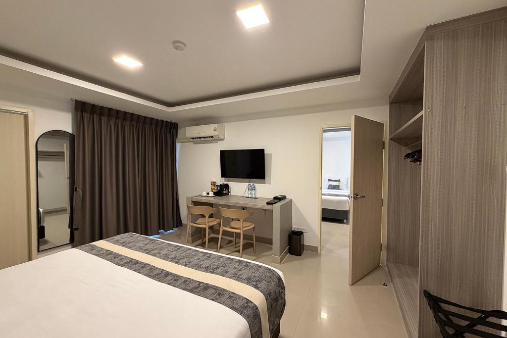 A furnished bedroom includes a desk, television, wardrobe and curtained window wall.