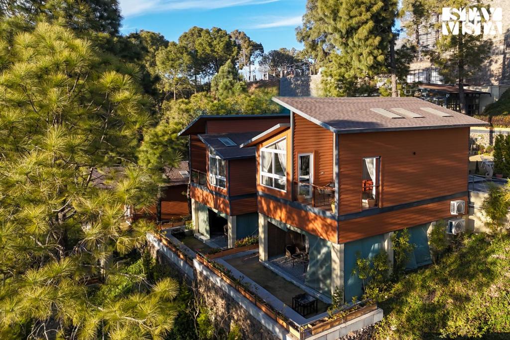 a house on a hill with trees at Sirmour Baag by Vaana - A part of StayVista in Nahna