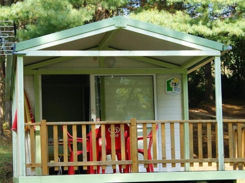 a screened in porch with red chairs on a deck at Chalet avec terrasse - 2 pers. - API-1-52-1592 in Saint-Girons