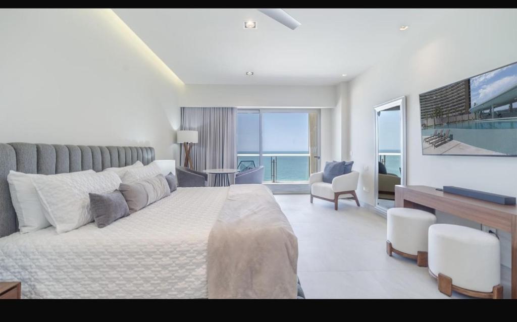 a white bedroom with a large bed and a television at Two bedroom Suite in Puerto Peñasco
