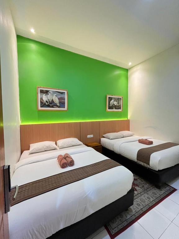 two beds in a room with a green wall at The Cabin Tugu Hostel in Yogyakarta