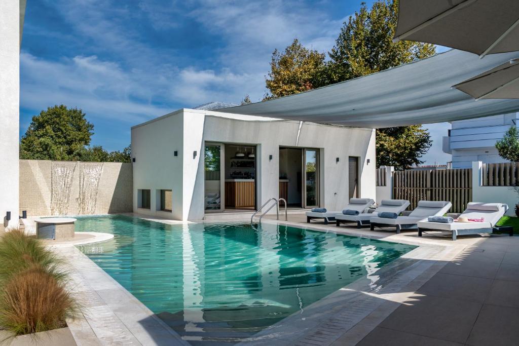 a swimming pool with chairs and a house at Palm View Suites in Kourouta