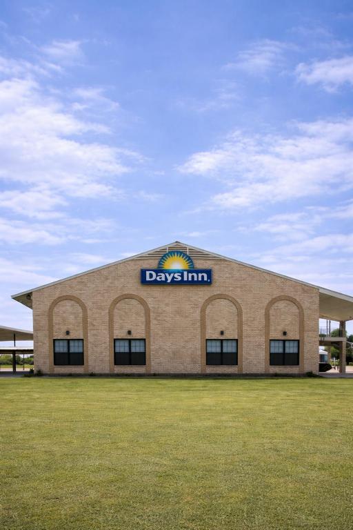 a large building with a day inn sign on it at Days Inn & Suites by Wyndham - Canton First Monday Trade Days in Canton