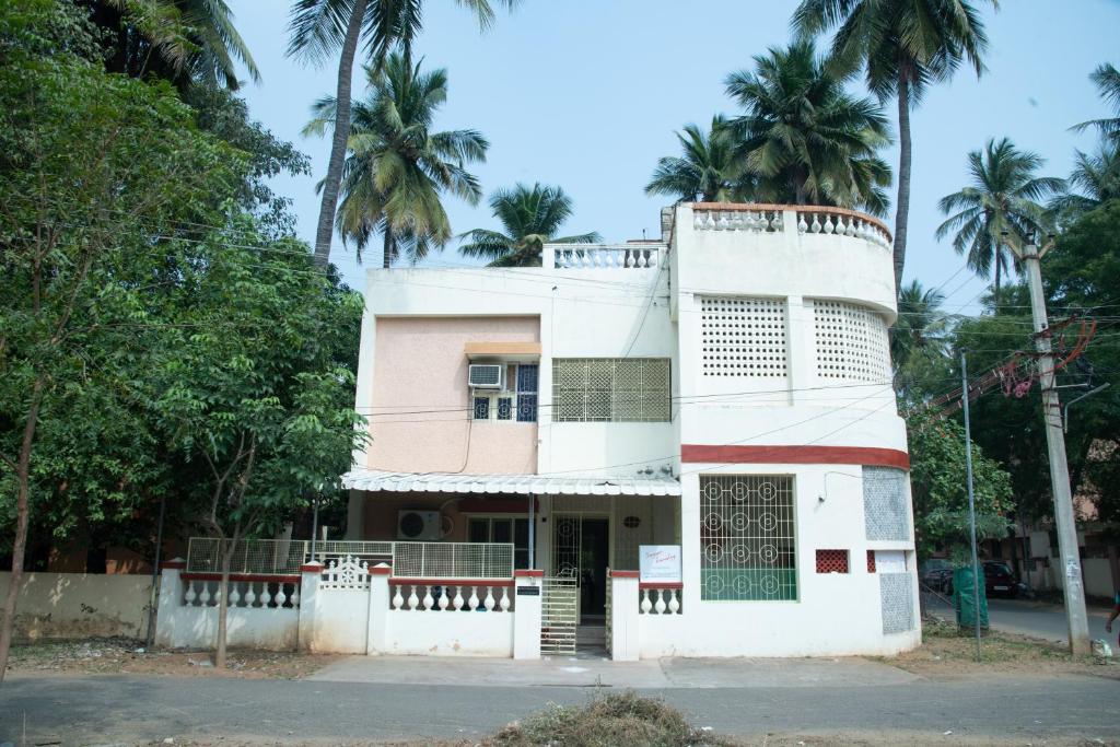 an old building with palm trees in the background at Thaayar Homestay by Highpoint in Tiruchirappalli