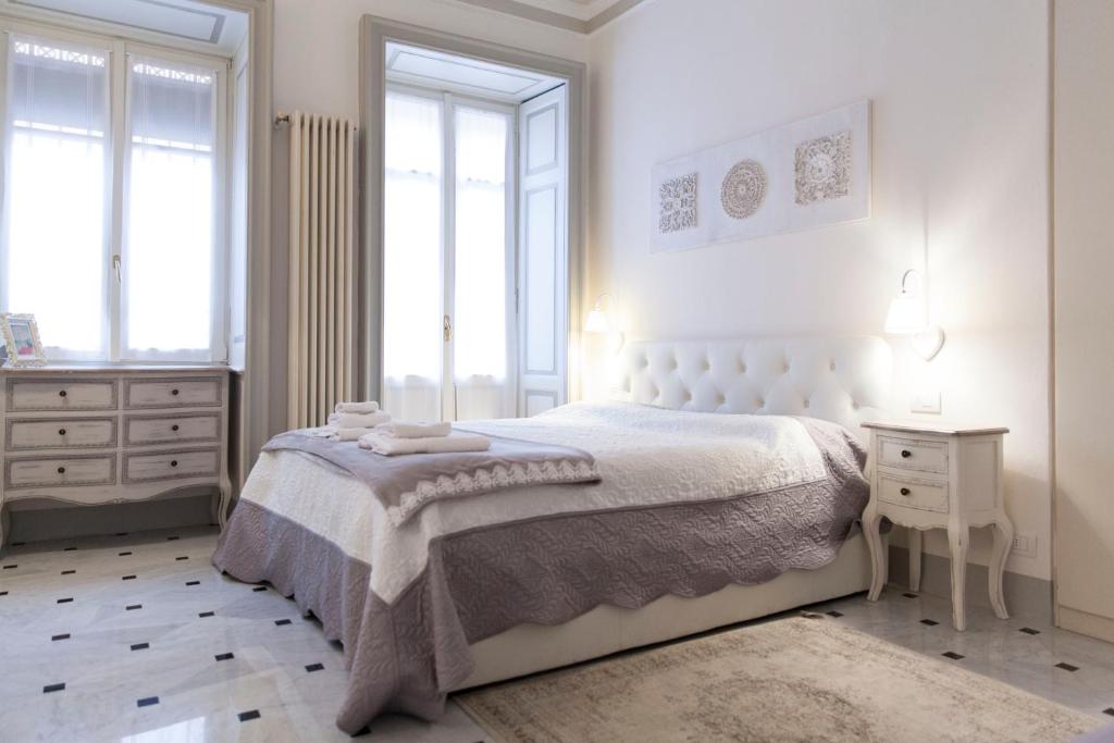 a white bedroom with a bed and a table and windows at The Como Secret Garden in Como