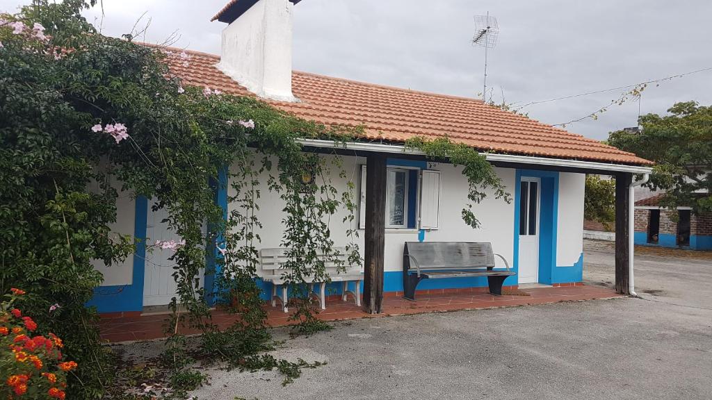 una casa azul y blanca con un banco delante en Casa da Felicidade en Pataias