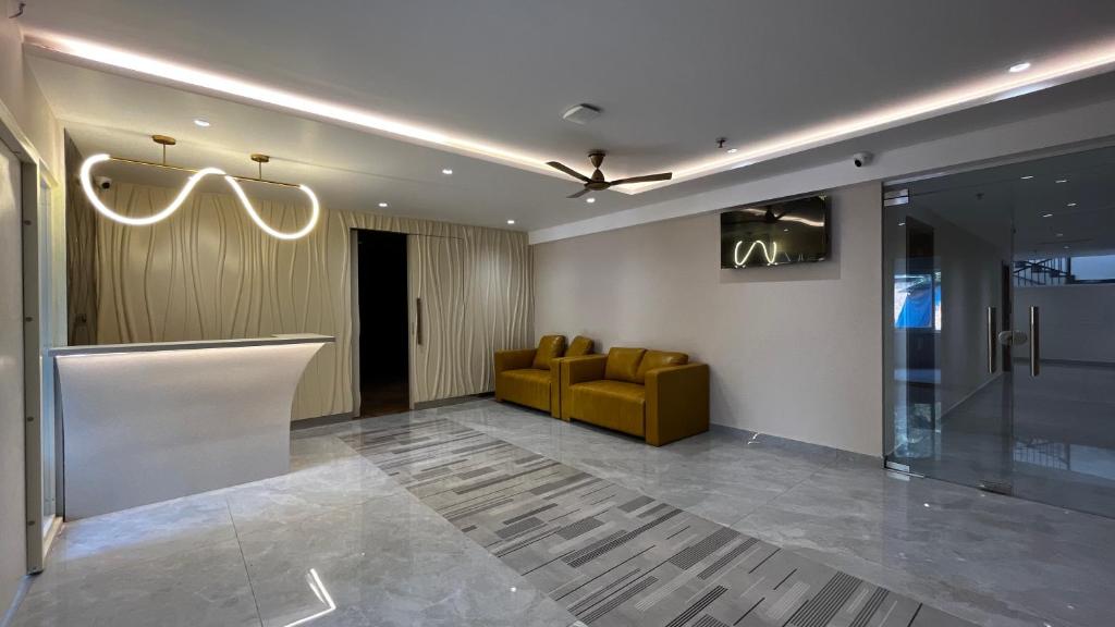 a lobby with a yellow chair and a couch at Cloud Nine Hotel in Kottayam