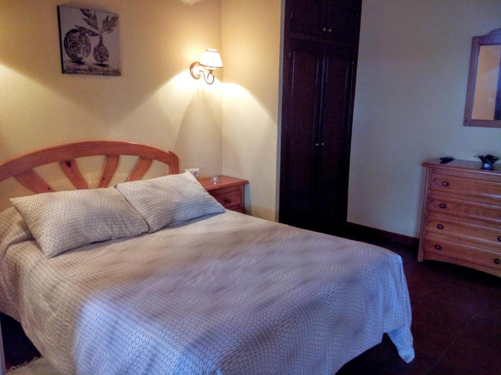 a bedroom with a bed and a dresser at Aparthotel Las Palomas in La Puebla de los Infantes