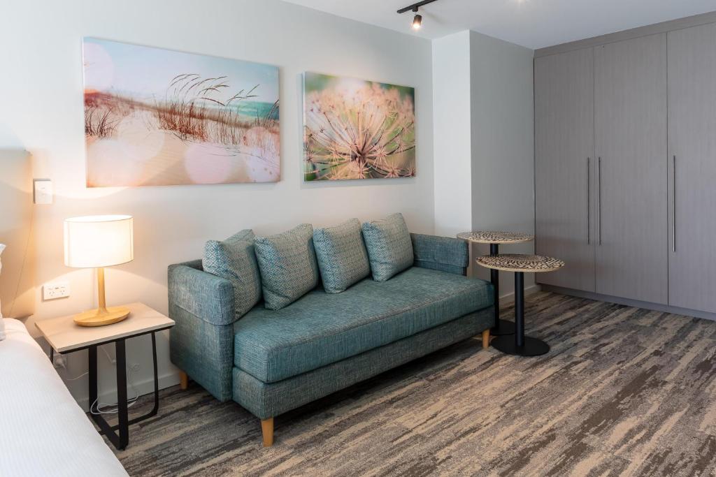 ein Wohnzimmer mit einer Couch und Gemälden an der Wand in der Unterkunft Nightelier Narrabeen in Narrabeen