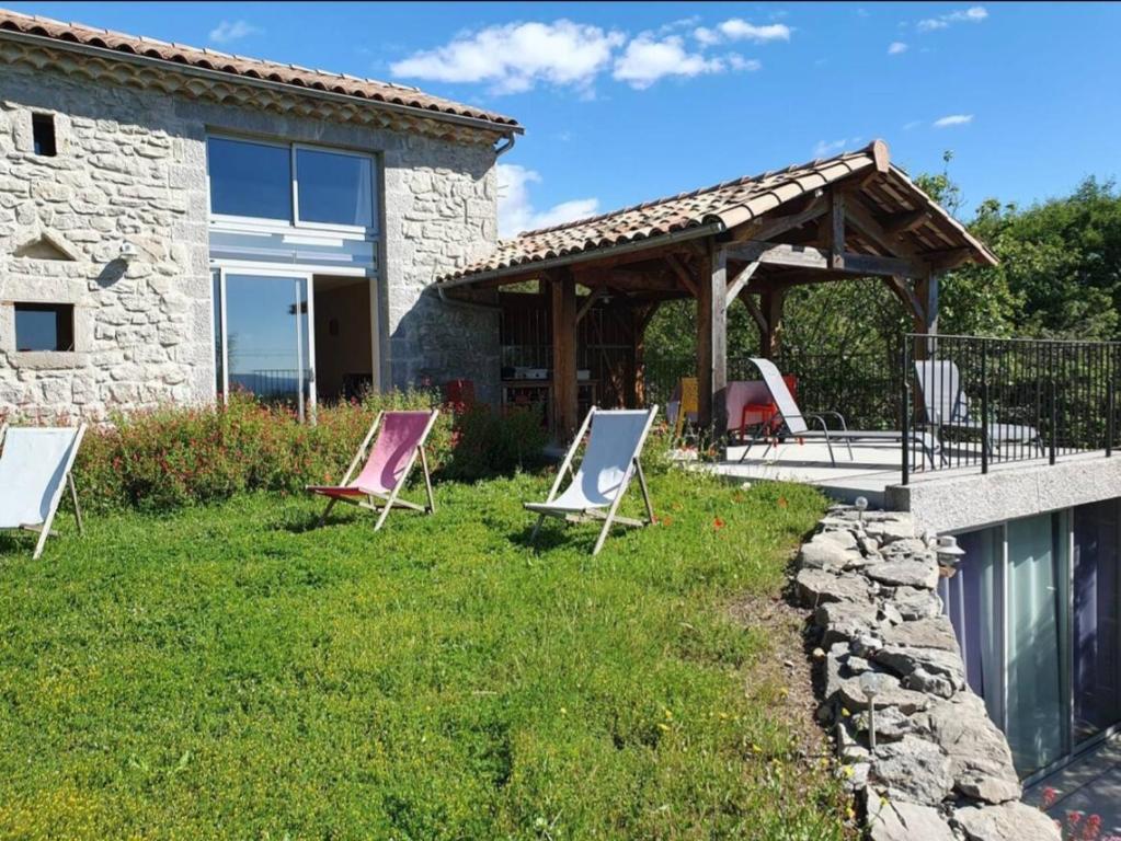 a group of chairs sitting on a lawn in front of a house at Le Trible in Labeaume