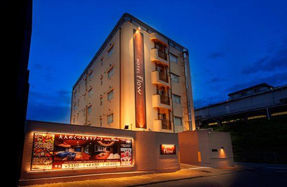 a tall building with a sign in front of it at Hotel FLOW in Misato