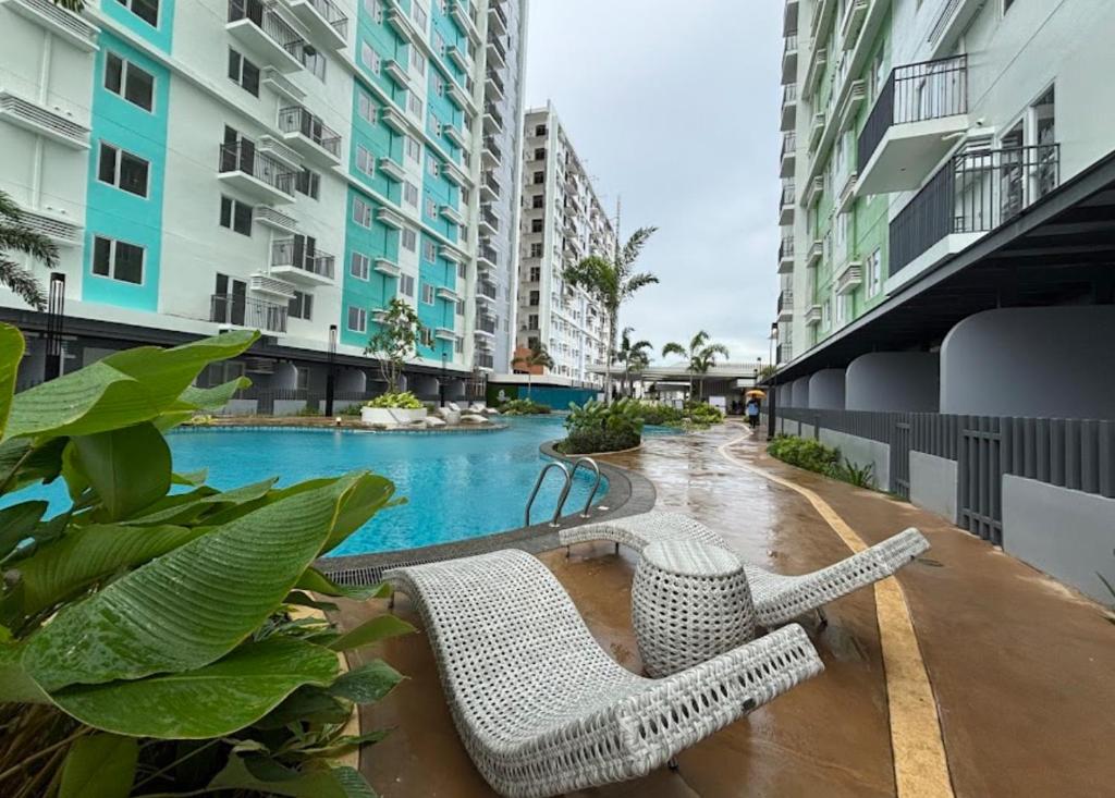 a couple of wicker chairs sitting next to a swimming pool at Clover88 Studio Room is in the City but with a seaview in Mandaue City