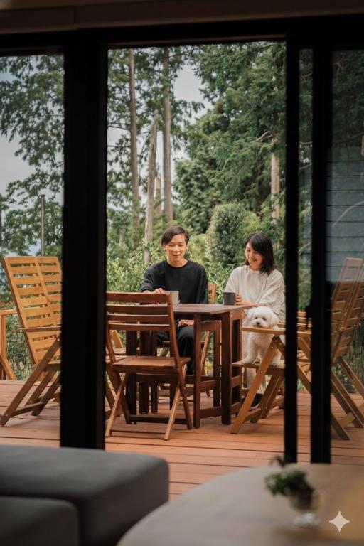 two people sitting at a table on a patio at 愛犬と休日を過ごすサウナハウス-COZY HOUSE Izukogen- in Ito