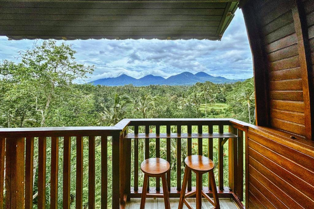 two stools on a balcony with a view of mountains at Four Mountains Villa Bedugul by AGATA in Bedugul