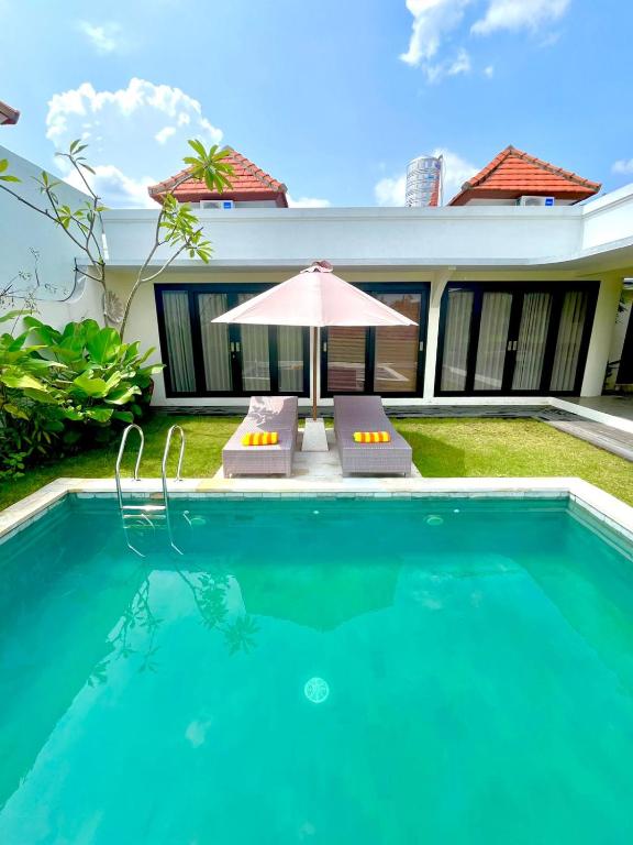 a swimming pool with two chairs and an umbrella at Villa Santé ubud in Ubud