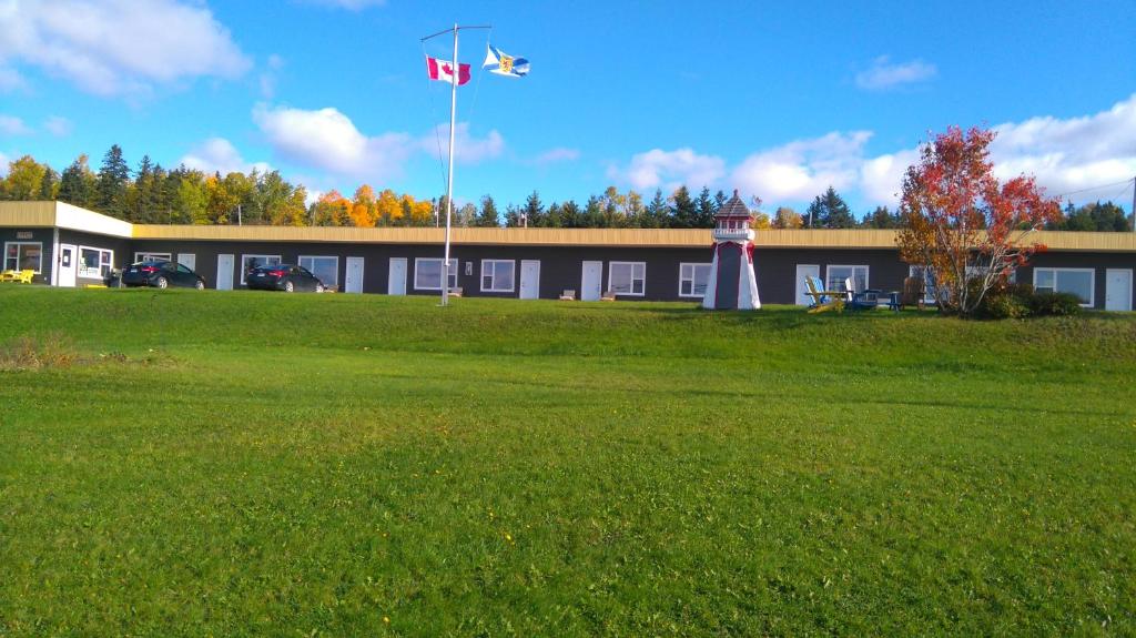 a building with a flag and a building with a grass field at Oasis Motel in Antigonish