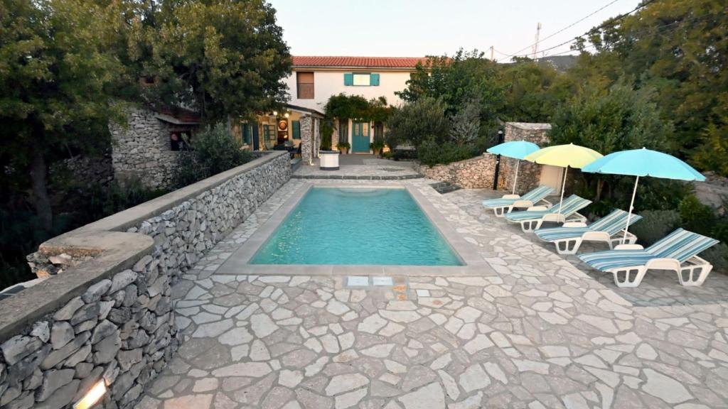 a swimming pool with chairs and umbrellas next to a house at Villa Buby by Villas Guide in Kraljevica