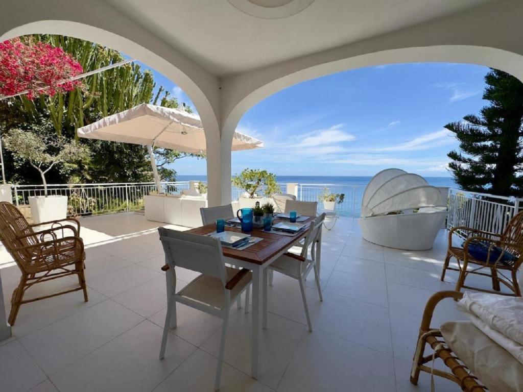 a dining room with a table and chairs and the ocean at Sicily Sea Villa Capo Zafferano in Santa Flavia