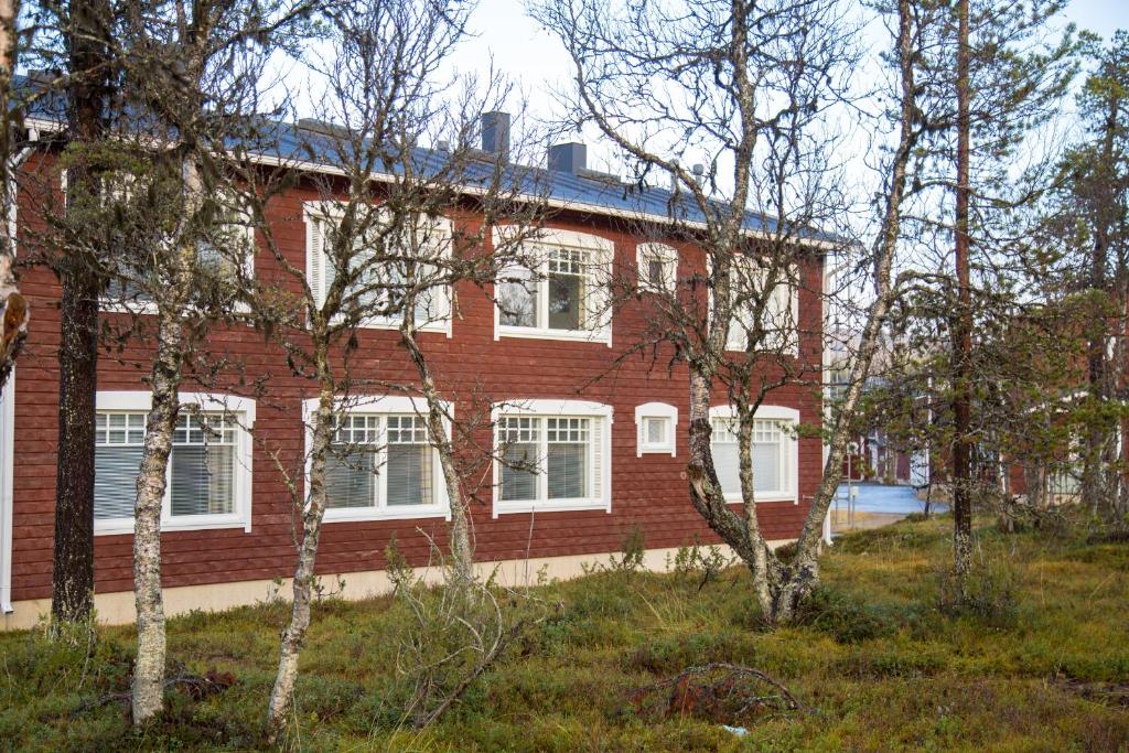 un edificio de ladrillo rojo con ventanas blancas y árboles en Apartments Rautulampi, en Saariselkä