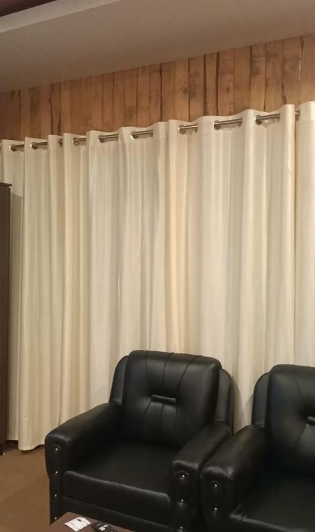 a room with two black chairs and white curtains at Ribhoi Jungle in Khānāpāra