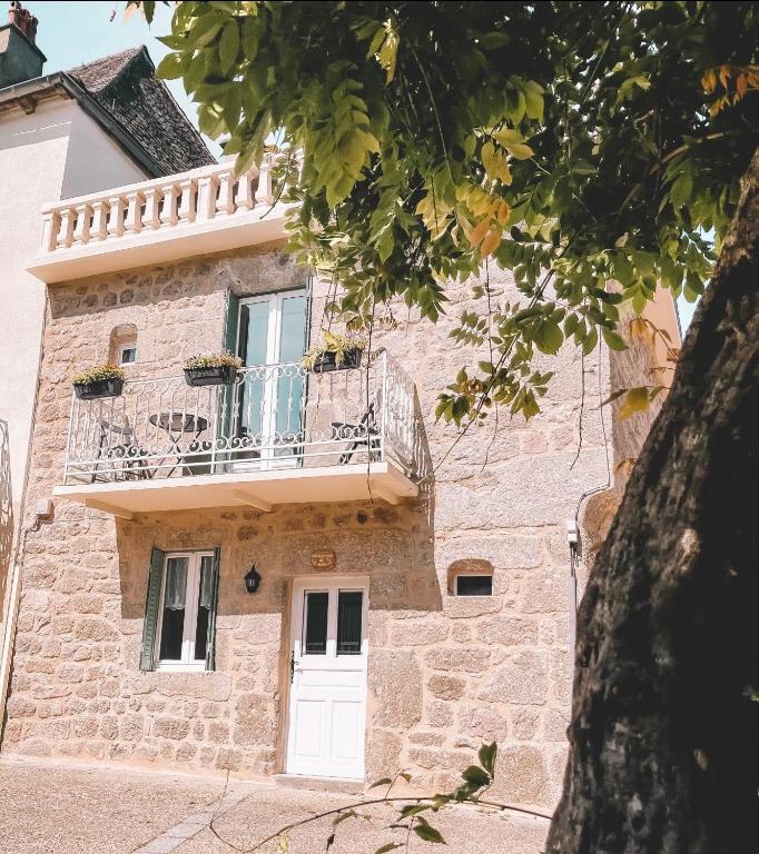 a building with a white door and a balcony at Le coin des Samariens - Étape Saint-Jacques in Golinhac