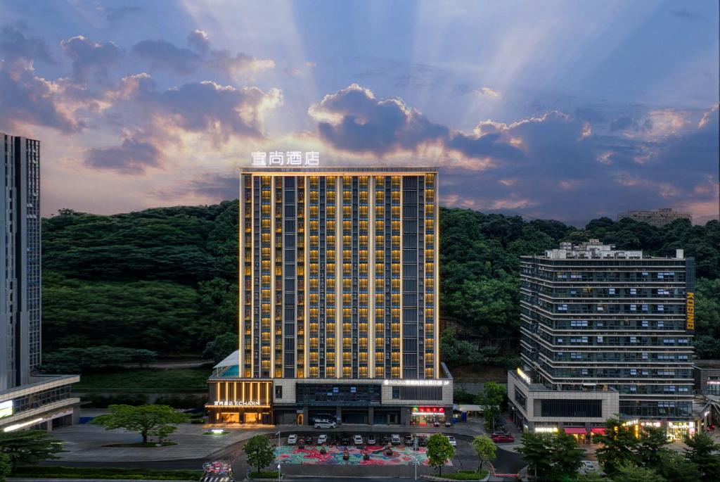 a tall building in a city at sunset at Echarm International Hotel Guangzhou Huangpu Flagship Shuixi Subway Station Branch - Free Deliver Service to Guangzhou Baiyun International Airport & Free Deliver Service to Canton Fair Complex During Canton Fair Period in Guangzhou
