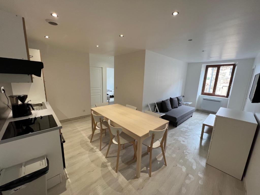 a kitchen and living room with a table and chairs at Signature Apartment in Pélussin
