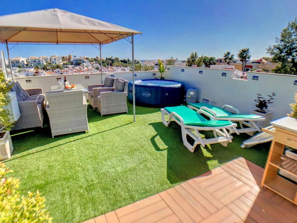 a patio with a table and chairs and an umbrella at Apartment Alpha - 2 Bedrooms, Private Rooftop Patio with Hot Tub, BBQ and View in Ferragudo