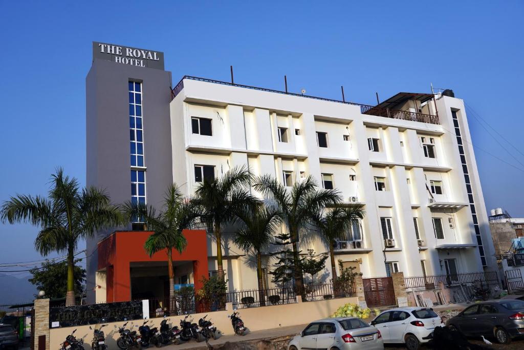 a white building with cars parked in front of it at The Royal Hotel in Haldwāni