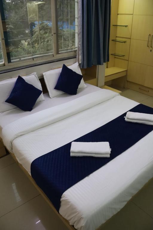 a large bed with blue and white pillows on it at Hotel krishnasai in Pune