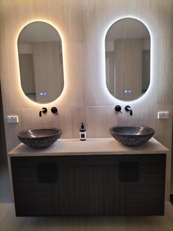two sinks in a bathroom with two mirrors at Maisie Haven in Brisbane