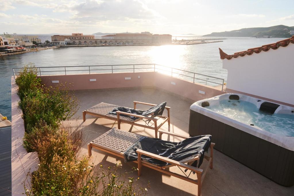 a balcony with two chairs and a hot tub on a ship at KALLINO Island Suites in Ermoupoli