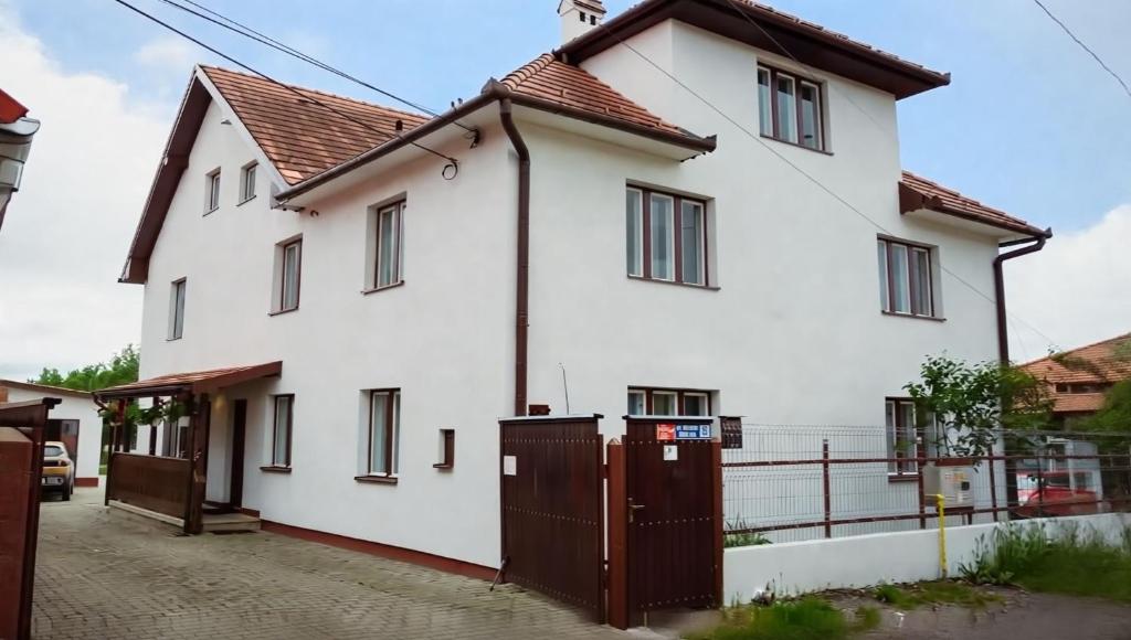 a white house with a gate in front of it at Akác Apartmanház in Odorheiu Secuiesc