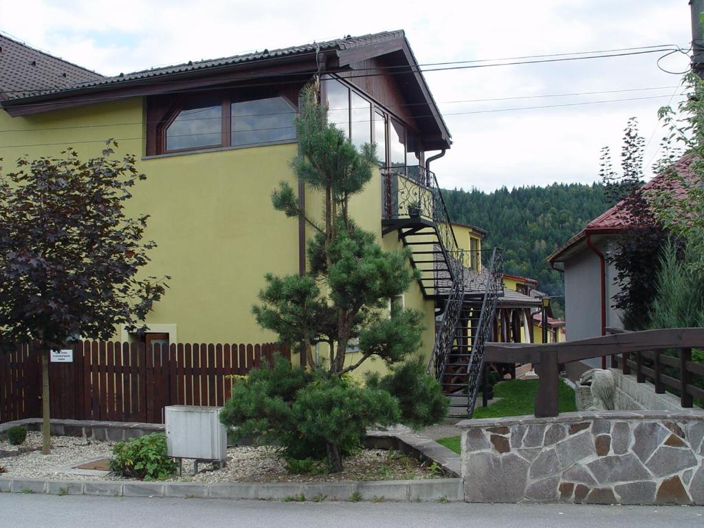 a yellow house with a staircase in front of it at Penzion Zlaty Orol in Helcmanovce