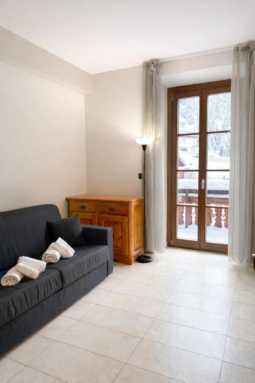 a living room with a couch and a window at Hostdomus - Mughetto Apartment in Pragelato