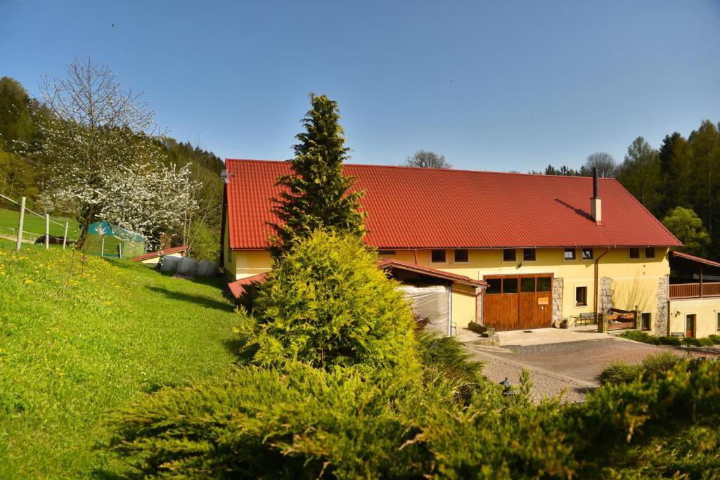 a house with a red roof on a green field at Penzion Tuček Adršpach in Adršpach