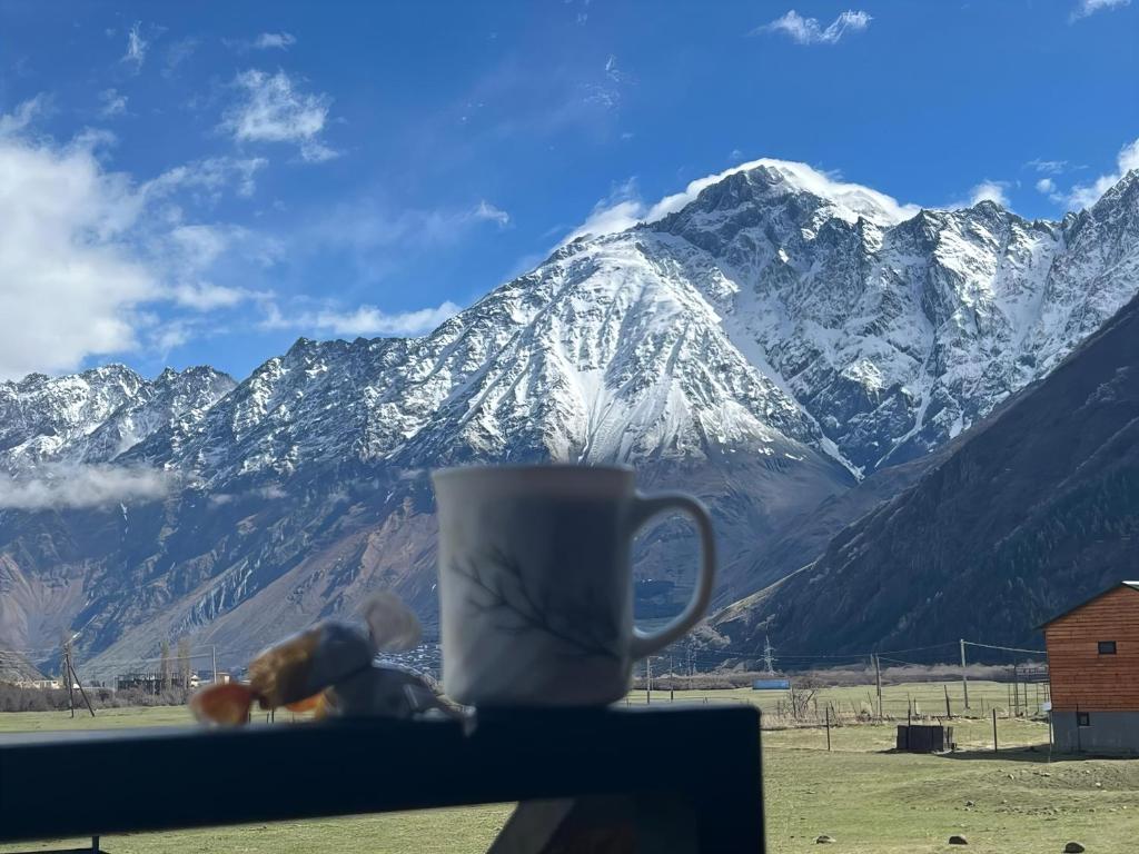 a coffee cup sitting on a table with a snow covered mountain at Achkhoti Paradise in Kazbegi