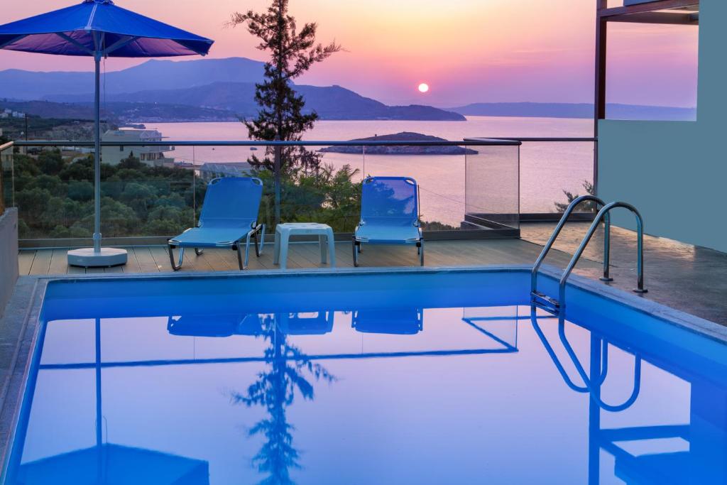 a swimming pool with two chairs and a sunset at Alexis Zorba Villa - private pool & sea view - 8 min walk to beach in Plaka