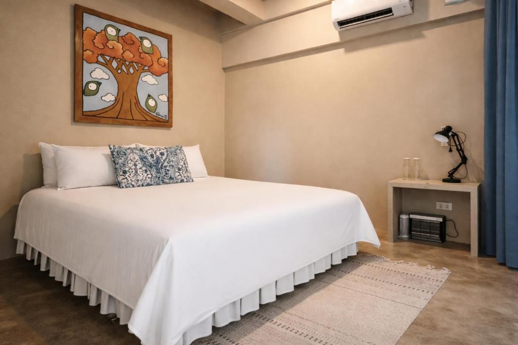 a bedroom with a white bed with a picture on the wall at Sleepy Gypsea Villa Siargao Swell in Catagnan