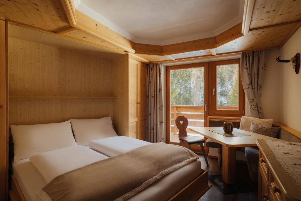 a bedroom with a bed and a desk and a window at Residence Ciasa Vedla in Badia