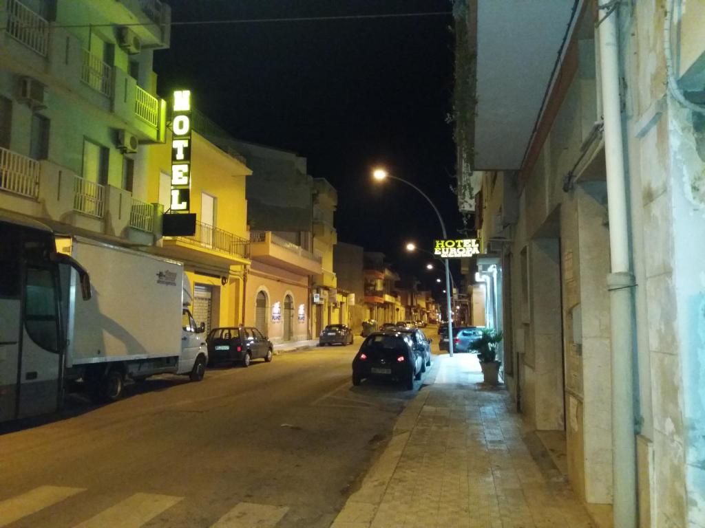 Una calle de la ciudad por la noche con coches aparcados en la calle en Hotel Europa en Vittoria