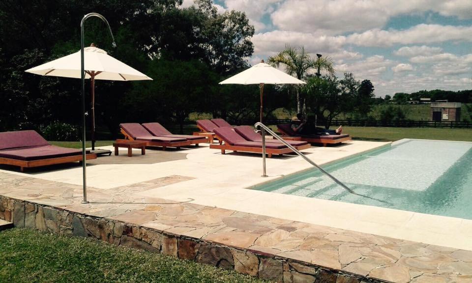 哥倫布的住宿－Noha Casa de Campo，游泳池旁配有两把遮阳伞和躺椅