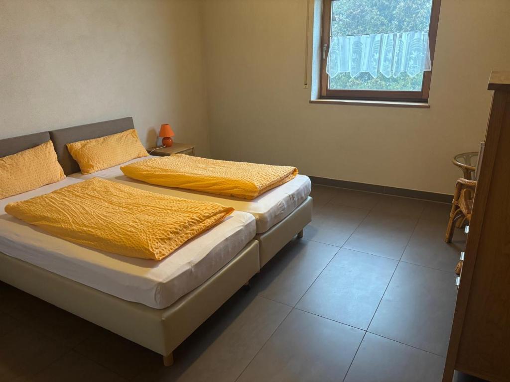 a bedroom with two beds with yellow sheets and a window at Panoramaferienwohnungen Stemler in Eulenbis