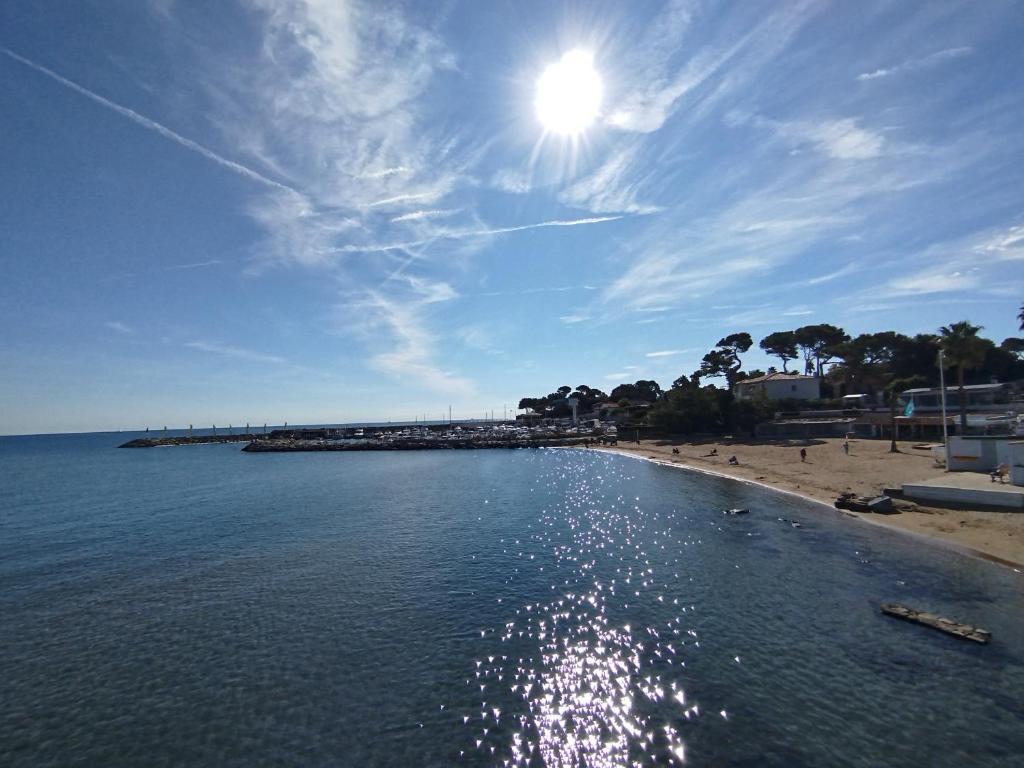 a beach with a pier and the sun in the sky at le victoire in Fréjus