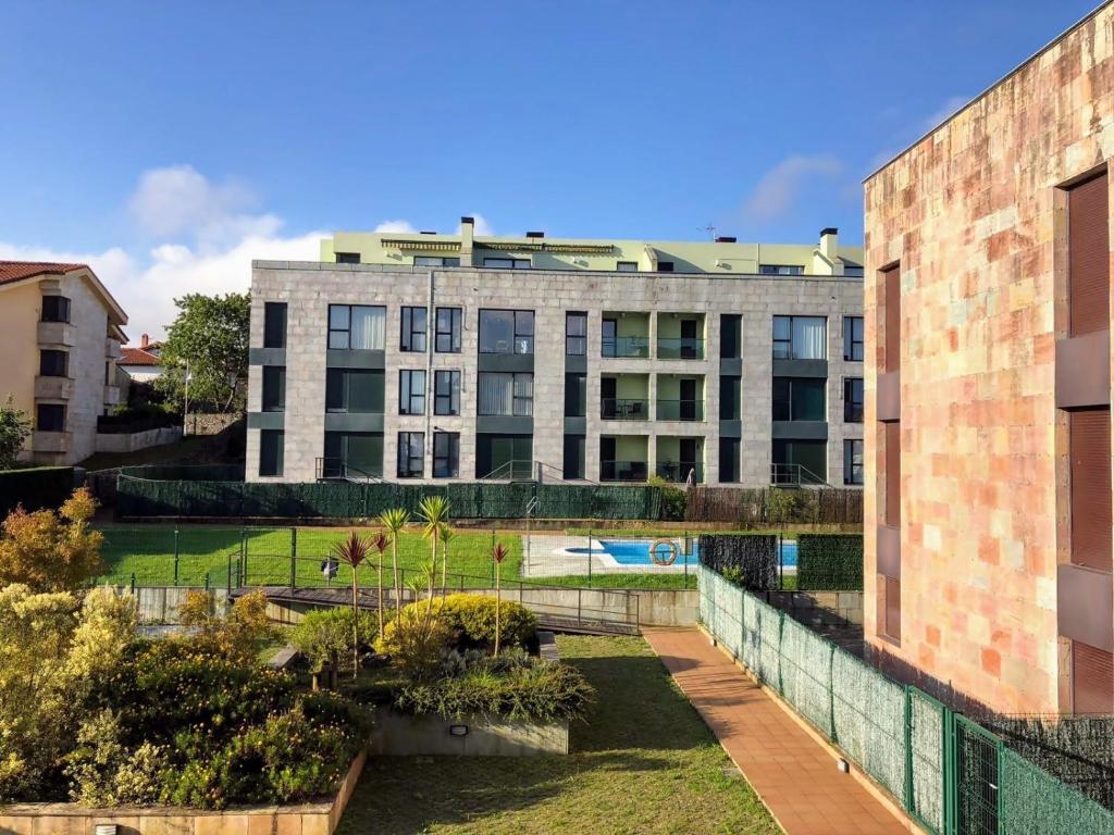 an apartment building with a garden in front of it at Llanes Celorio Piscina y Playa – El Castro Borizu in Celorio