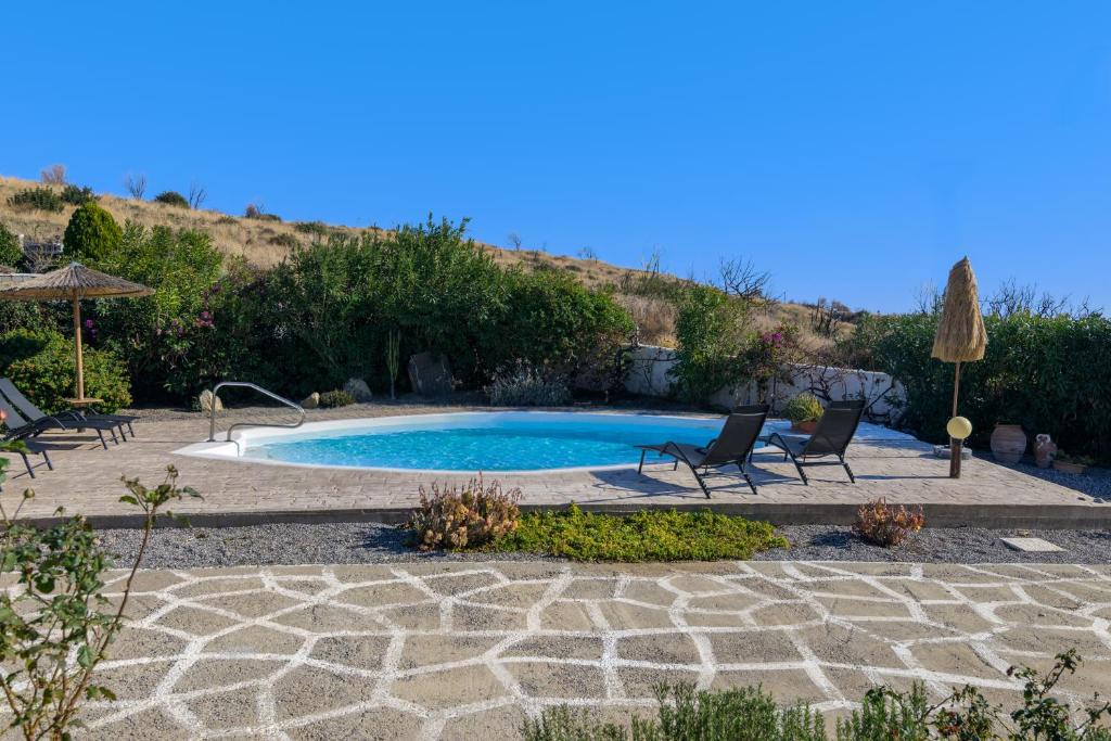 a swimming pool with two chairs and an umbrella at Villa Nastazia in Kiotari