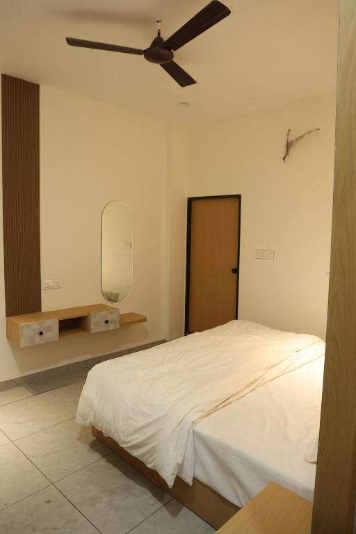a bedroom with a bed and a ceiling fan at Hotel Shiv Om in Ujjain