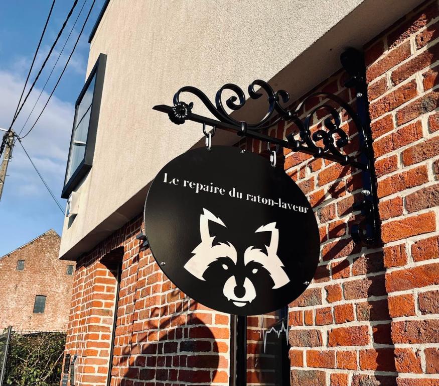 a sign on the side of a brick building at Le repaire du raton laveur in Rance